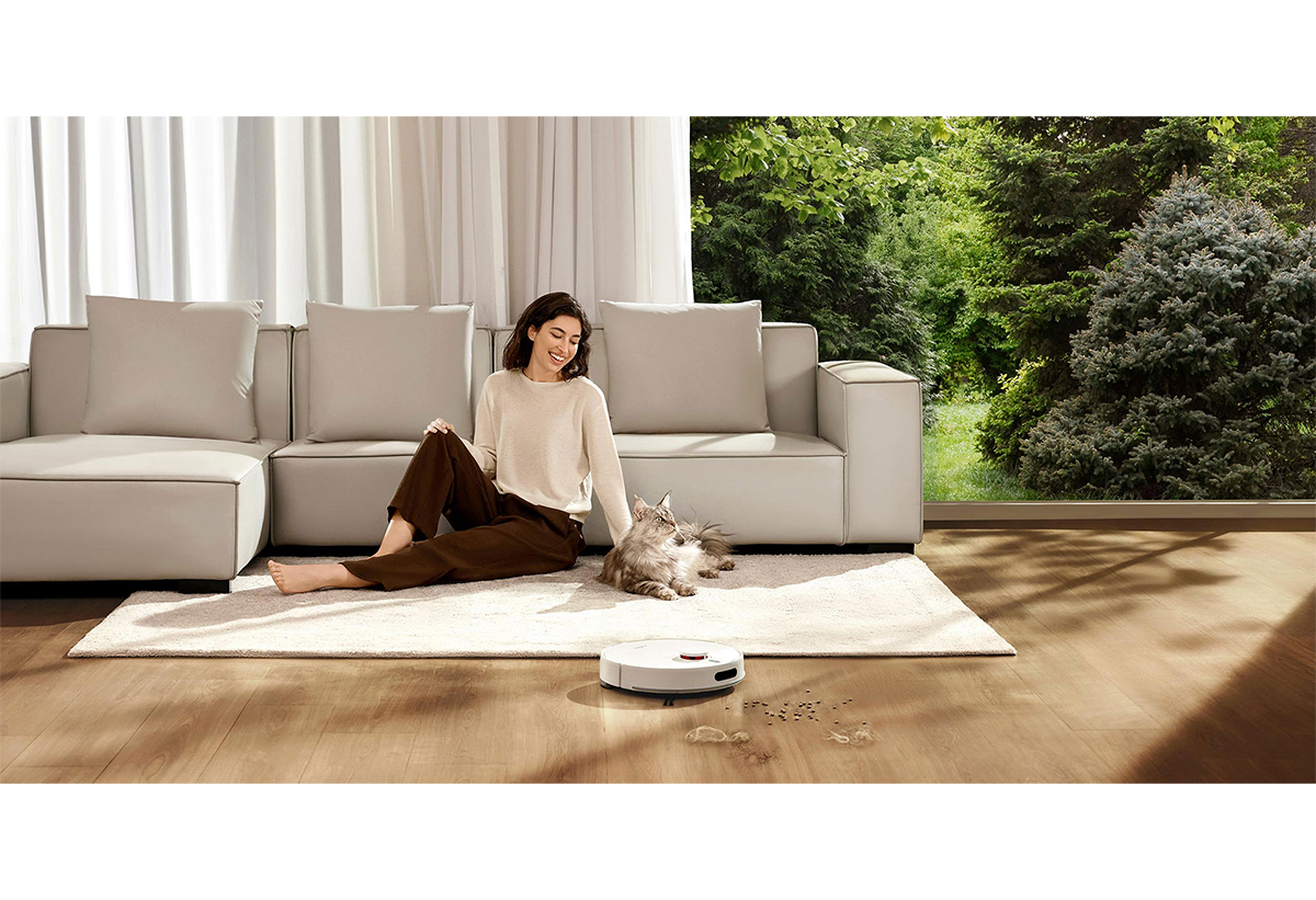 Απεικονίζεται μια γυναίκα να κάθεται στο πάτωμα του σαλονιού της με την γάτα της και την σκούπα να βρίσκεται σε λειτουργία.